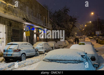 Jerusalem, Israel. 13th December 2013. Pedestrians walk past a snow-covered street in Jerusalem. A heavy storm in Israel, ongoing for three days straight, has paralyzed the traffic across the country with Tel Aviv's airport shut down and soldiers dispatched to rescue stranded drivers on highways. Police have called on citizens to stay indoors, saying driving on icy highways may be a 'real life threat' in what meteorologists dubbed as the strongest snow storm since 1953. Jerusalem is covered with snow and all entry roads are blocked. Credit:  Xinhua/Alamy Live News Stock Photo