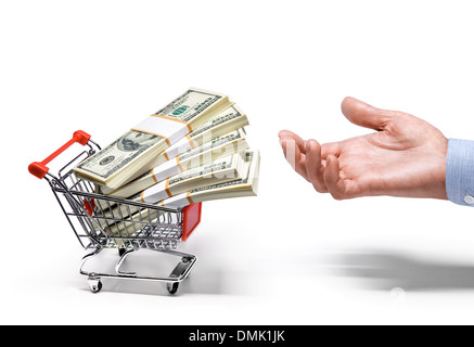 Businessman's hand & shopping cart full of stacks of American dollar banknotes Stock Photo