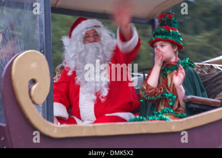 Wimborne, Dorset, UK. 14th December 2013. Crowds turn out to watch the 25th Wimborne Save The Children Christmas Parade. Father Christmas, Santa Claus waving to the crowds with Elf helper. Credit:  Carolyn Jenkins/Alamy Live News Stock Photo