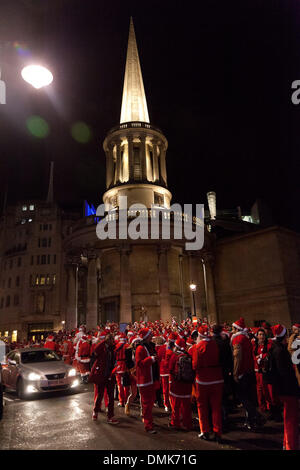 London, UK. 14th of December 2013 Hundreds of revelers of the annual Santa Con event, gathered outside BBC Broadcasting House in Portland Place. They sung and danced to mobile music players spreading their Christmas cheer to passers by. Police officers arrived to ensure the road was clear. Credit:  nelson pereira/Alamy Live News Stock Photo