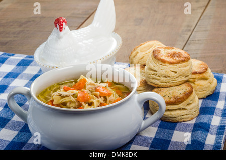 Warm chicken soup and fresh baked biscuits on blue checked cloth Stock Photo