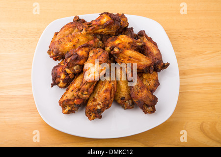 Mesquite barbecued chicken wings on a square white plate and wood table Stock Photo