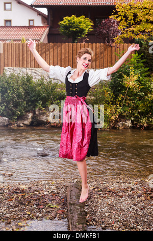 Beautiful girl in a dirndl posing at a stream Stock Photo