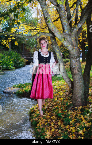 Beautiful woman in a dirndl under an autumn tree Stock Photo