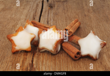 Iced Christmas star shaped biscuits biscuits and cinnamon sticks on old weathered wood Stock Photo