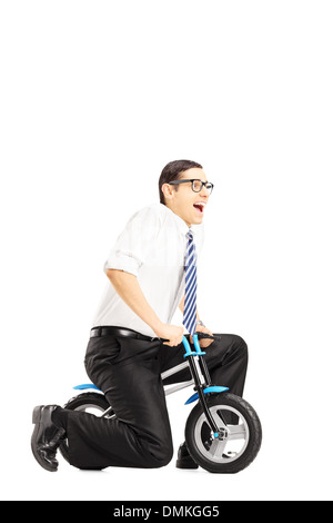 Excited young businessperson riding a small bicycle Stock Photo