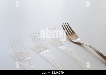 Three plastic forks and a stainless steel one. Stock Photo