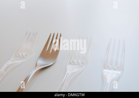 Three plastic forks and a stainless steel one. Stock Photo