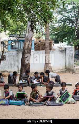 Rural Indian village school children in an outside class writing on a chalk tablets. Andhra Pradesh, India Stock Photo