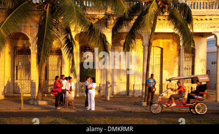 Local people and bicycle taxi in evening street scene, Cienfuegos ( UNESCO world heritage site ), Cuba, Caribbean, Latin America Stock Photo