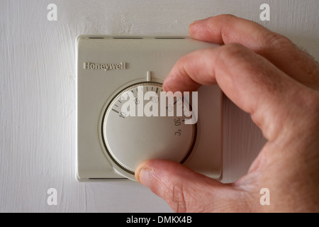 Honeywell central heating thermostat being turned down to 18 degrees Stock Photo