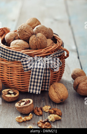 Walnuts in wicker basket on wooden background Stock Photo