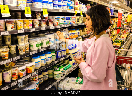 A teenaged girl trying to make up her mind whether to buy regular or non-fat yogurt in a supermarket Stock Photo
