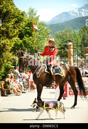 Royal Canadian Mounted Police officer mounted on a horse, wearing a formal red serge uniform parade through Whistler BC, Canada Stock Photo