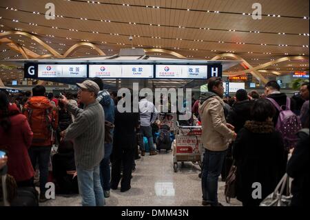 Kunming, China's Yunnan Province. 15th Dec, 2013. Stranded passengers wait in line to reschedule their tickets at the terminal building of the airport of Kunming, capital of southwest China's Yunnan Province, Dec. 15, 2013. Kunming, the Spring City, witnessed a snowfall from Sunday to early Monday due to the advent of severe cold air. Snow began to affect the airport at 9 a.m. (0100 GMT) on Sunday. As many as 259 flights have been canceled as of midnight of Sunday, according to the airport. Credit:  Zhang Keren/Xinhua/Alamy Live News Stock Photo