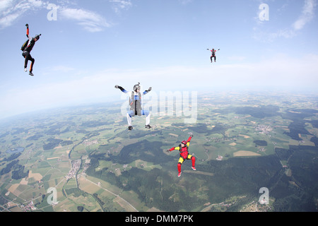 Freefly skydiving team is training formation sit-flying over a spectacular land and fields scenery in the sky with 120 MPH. Stock Photo