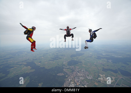 Freefly skydiving team is training formation sit-flying over a spectacular land and fields scenery in the sky with 120 MPH. Stock Photo