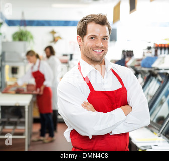 Confident Male Butcher Standing Arms Crossed At Store Stock Photo