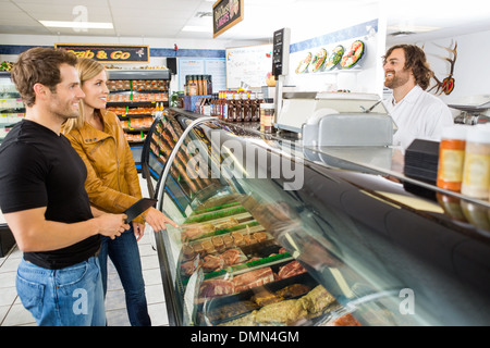 Salesman Attending Customers At Butcher's Shop Stock Photo