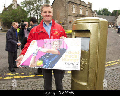 Dunblane postman John Elliot with a commemerative Andy Murray stamp at newly painted gold post box following Murray's win at Stock Photo