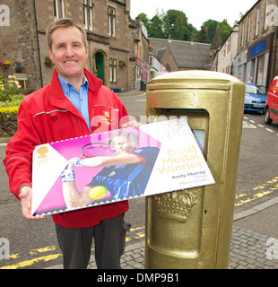 Dunblane postman John Elliot with a commemerative Andy Murray stamp at newly painted gold post box following Murray's win at Stock Photo