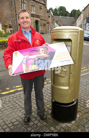 Dunblane postman John Elliot with a commemerative Andy Murray stamp at newly painted gold post box following Murray's win at Stock Photo