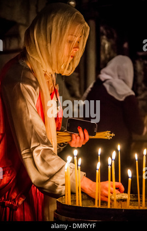 A Christian pilgrim women lights prayer candles inside the Church of the Holy Sepulchre. Stock Photo