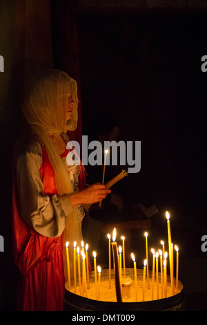 A Christian pilgrim women lights prayer candles inside the Church of the Holy Sepulchre. Stock Photo