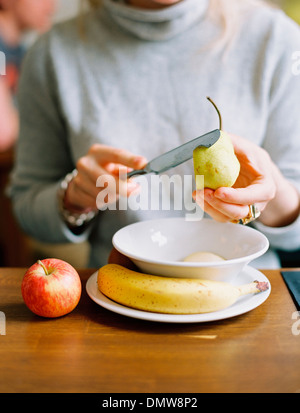 A woman slicing a fresh pear. Apple and banana. Stock Photo