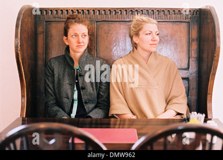 Traditional pub seat with a high back and curved sides. Two women sitting at a table. Stock Photo