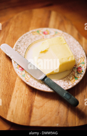 A decorated plate and a half used block of butter. Knife. Stock Photo