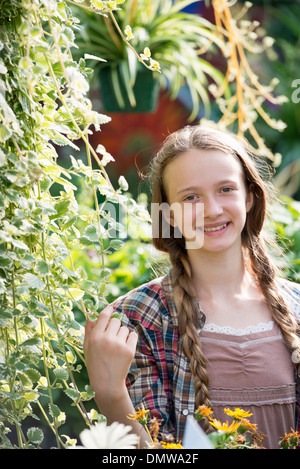 Summer on an organic farm. A young girl in a plant nursery full of flowers. Stock Photo