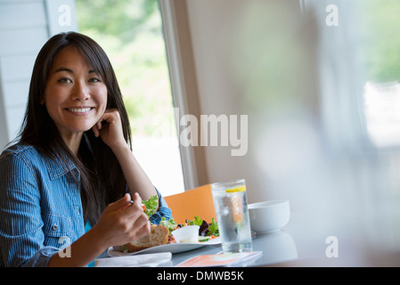 A woman seated eating in a cafe. Stock Photo