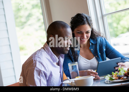A couple seated looking at a digital tablet. Stock Photo