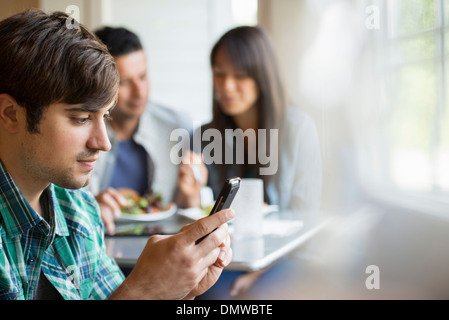 Three people seated at a cafe table. Stock Photo