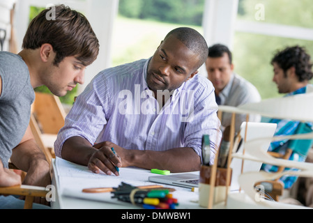 Two men seated one drawing on paper Stock Photo