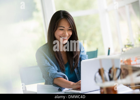 A woman in an office working at a laptop computer. Stock Photo