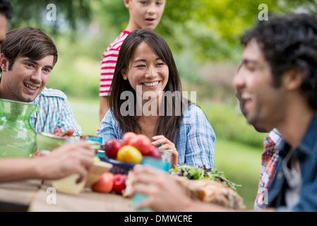 A summer party outdoors. Adults and children around a table. Stock Photo