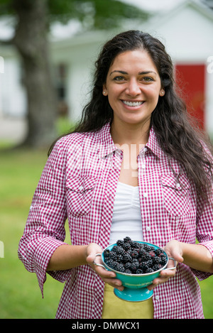 A woman holding a bowl of freshly picked blackberries. Stock Photo