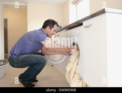 A man putting  laundry into  washing machine. Stock Photo
