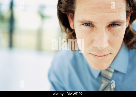 A young man with curly brown hair wearing a blue shirt and tie. Stock Photo
