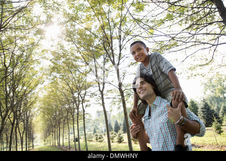 A man giving a boy a piggyback in  woods. Stock Photo