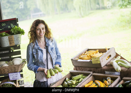 An organic fruit and vegetable farm. A young woman sorting vegetables. Stock Photo