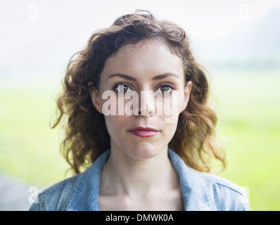 A young woman in a rural landscape with windblown curly hair. Stock Photo