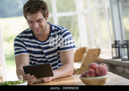A man sitting at a table using a digital tablet. Stock Photo
