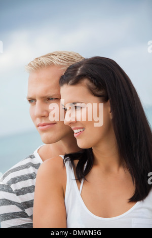 Loving couple enjoy a quiet tender moment as they stand in a close embrace staring off to the left of the frame in contentment Stock Photo