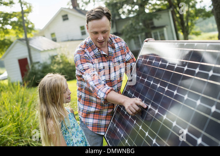 A man and a young girl looking at a solar panel in a garden. Stock Photo