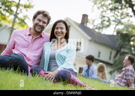 A couple sitting grass at a summer party. Stock Photo