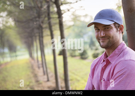 A man leaning against a tree looking at camera. Stock Photo