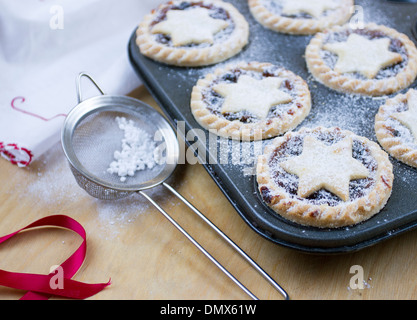 Home made icing sugar dusted mince pies in baking tray Stock Photo